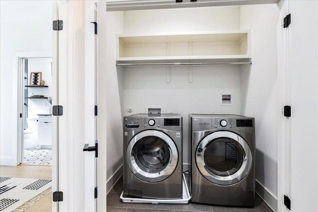 clothes washing area with laundry area, washing machine and dryer, baseboards, and wood finished floors