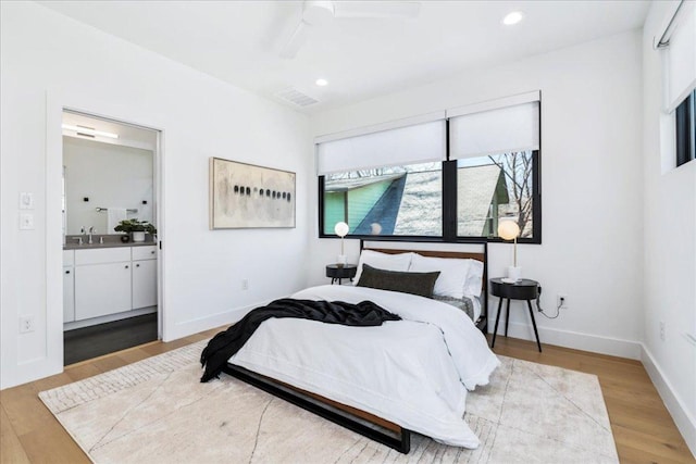 bedroom featuring visible vents, baseboards, ensuite bathroom, light wood-type flooring, and recessed lighting