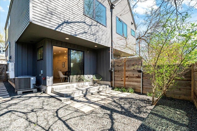 rear view of house with a patio, board and batten siding, cooling unit, and a fenced backyard