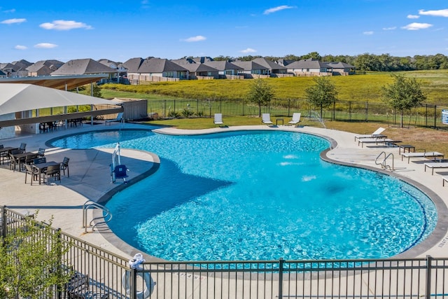 pool with a lawn, a patio area, fence, and a residential view