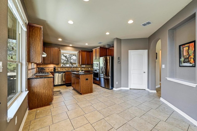 kitchen with a sink, visible vents, appliances with stainless steel finishes, a center island, and dark countertops