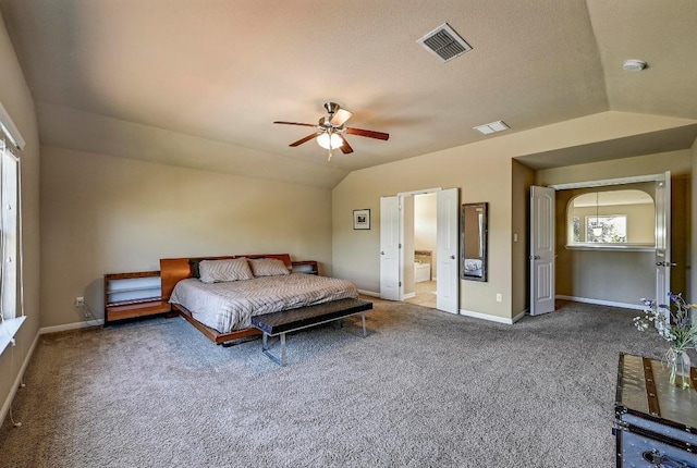 carpeted bedroom with lofted ceiling, visible vents, ensuite bathroom, ceiling fan, and baseboards