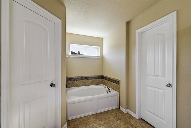 bathroom with a garden tub and a textured ceiling