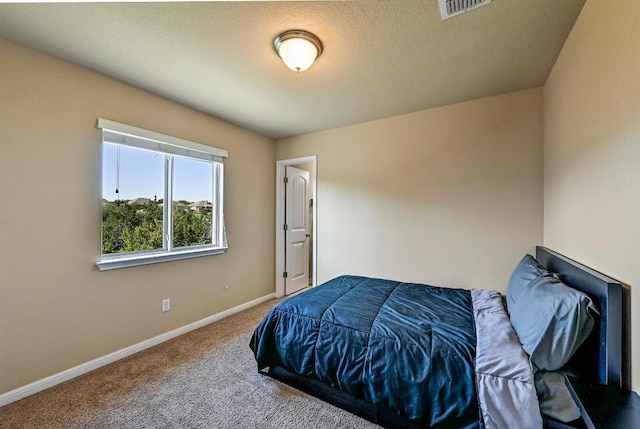 carpeted bedroom featuring visible vents, a textured ceiling, and baseboards