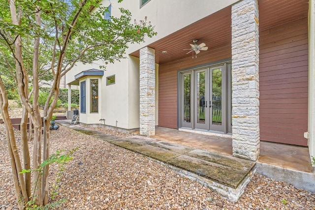 entrance to property with ceiling fan, stone siding, and french doors