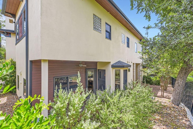 back of house with a ceiling fan and stucco siding