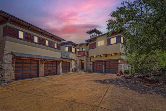 view of front of home featuring stone siding, concrete driveway, an attached garage, and stucco siding