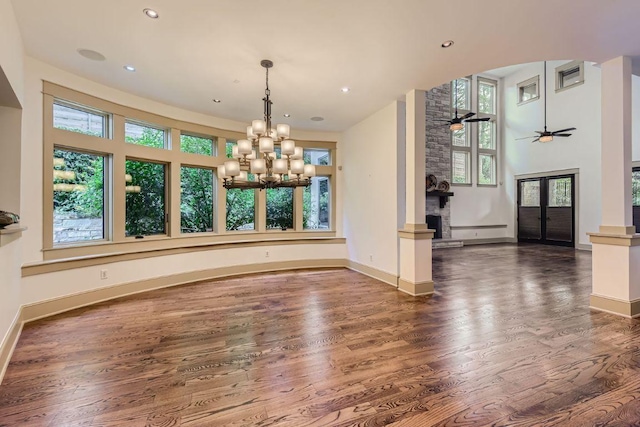 unfurnished dining area with a wealth of natural light, baseboards, wood finished floors, and ceiling fan with notable chandelier