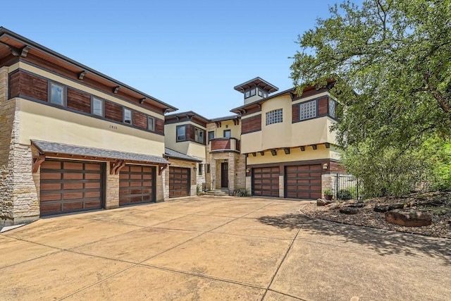 view of front of property with an attached garage, stone siding, driveway, and stucco siding