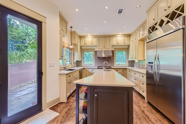 kitchen with tasteful backsplash, visible vents, wood finished floors, light countertops, and built in fridge