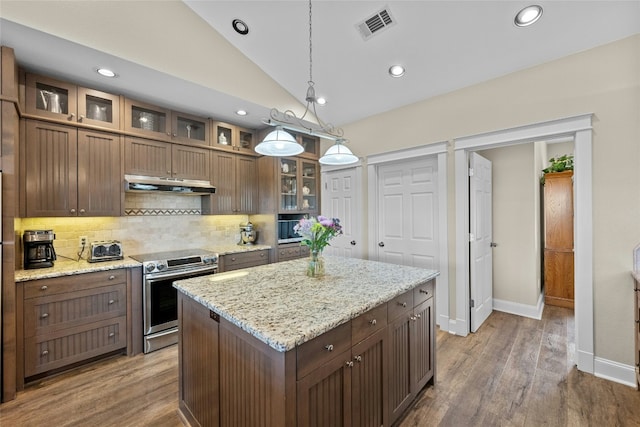 kitchen with tasteful backsplash, visible vents, electric stove, vaulted ceiling, and under cabinet range hood