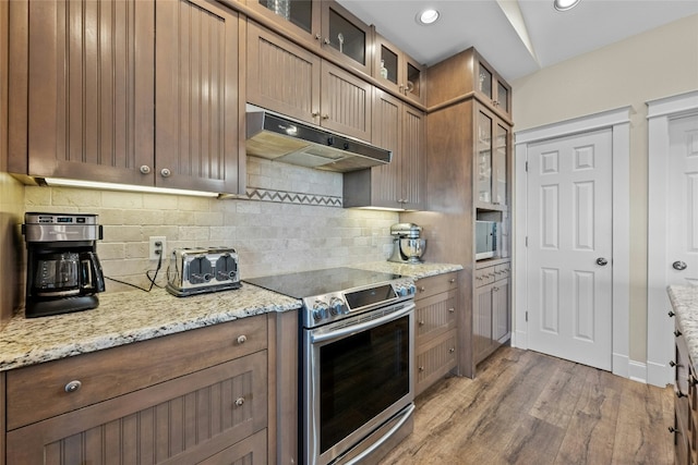 kitchen featuring recessed lighting, under cabinet range hood, stainless steel appliances, decorative backsplash, and light wood finished floors