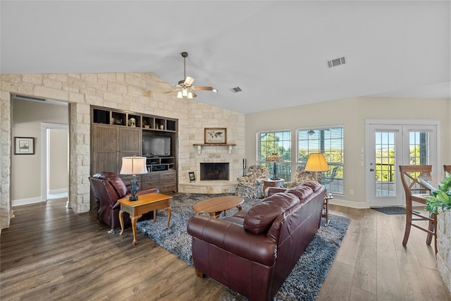 living room featuring lofted ceiling, ceiling fan, a stone fireplace, wood finished floors, and visible vents