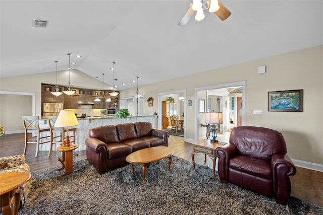 living area with lofted ceiling, visible vents, and wood finished floors