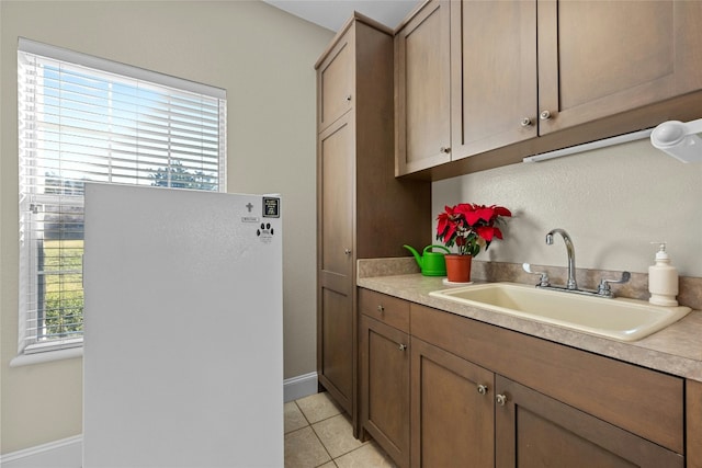 kitchen featuring light tile patterned floors, baseboards, light countertops, and a sink