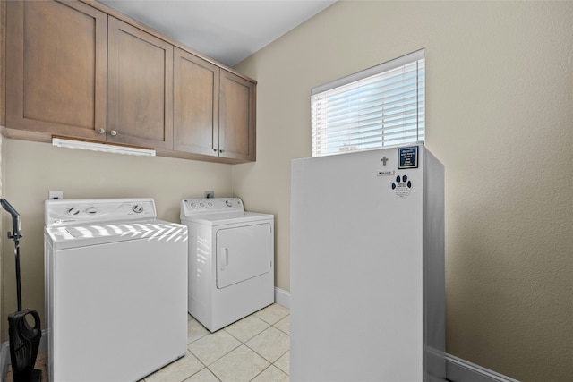 laundry room with washer and dryer, cabinet space, and light tile patterned flooring