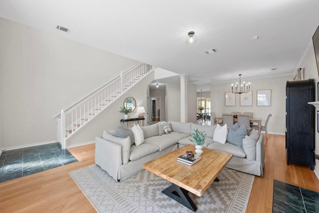 living room featuring visible vents, a notable chandelier, wood finished floors, and stairs