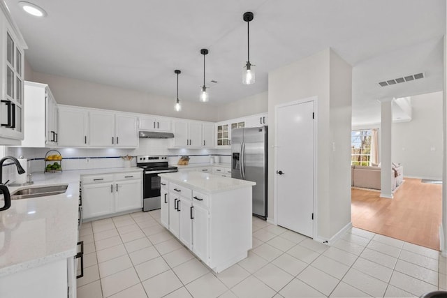 kitchen featuring under cabinet range hood, light tile patterned floors, decorative backsplash, stainless steel appliances, and a sink