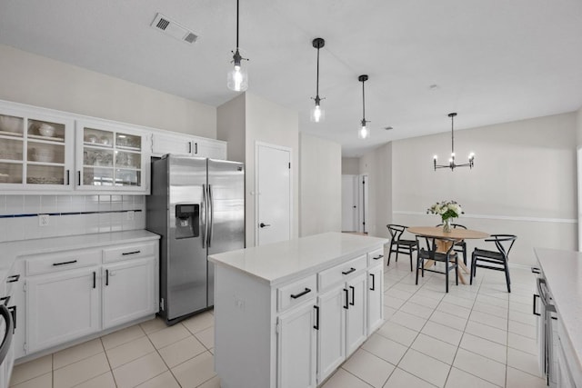 kitchen featuring visible vents, glass insert cabinets, light tile patterned floors, decorative backsplash, and stainless steel fridge