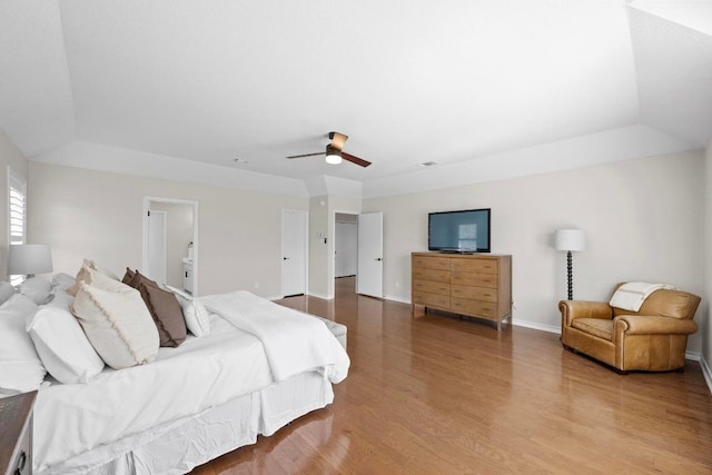 bedroom with a raised ceiling, wood finished floors, baseboards, and ceiling fan