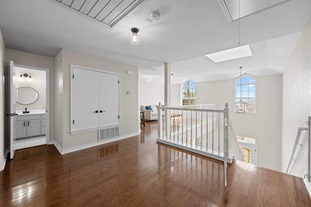 spare room with visible vents, baseboards, attic access, wood finished floors, and a sink