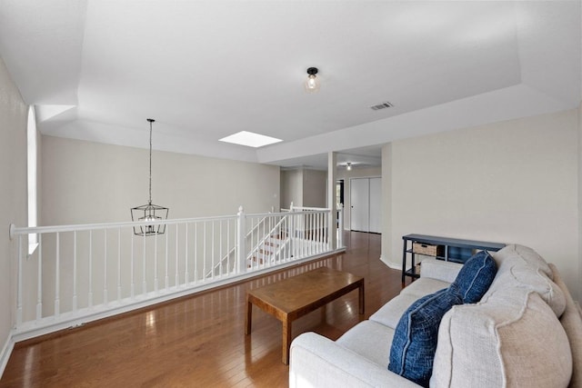 living area with visible vents, an upstairs landing, wood finished floors, a skylight, and baseboards