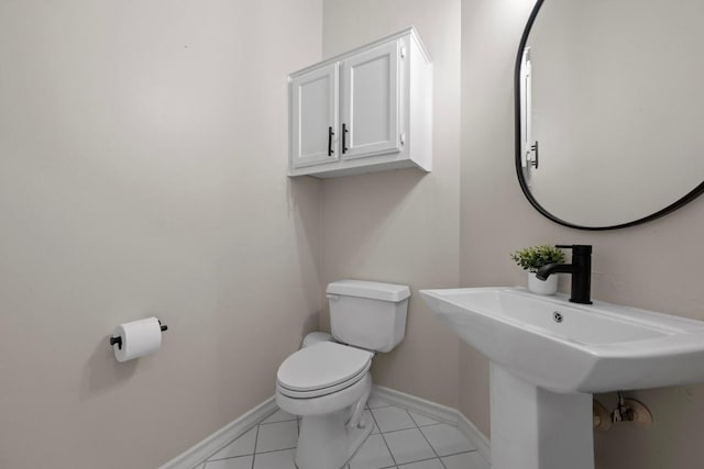 half bathroom with tile patterned floors, toilet, baseboards, and a sink