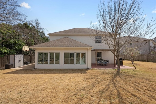 rear view of house with a patio, a lawn, roof with shingles, and fence