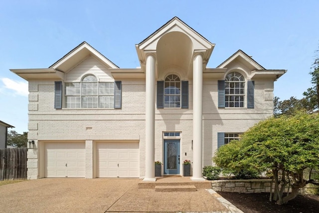 neoclassical / greek revival house featuring brick siding, concrete driveway, a garage, and fence