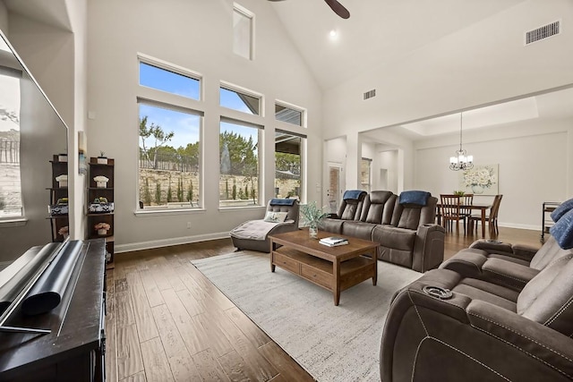 living room with baseboards, visible vents, wood finished floors, and ceiling fan with notable chandelier