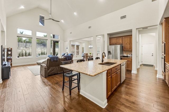 kitchen featuring brown cabinets, stainless steel appliances, visible vents, dark wood-type flooring, and open floor plan