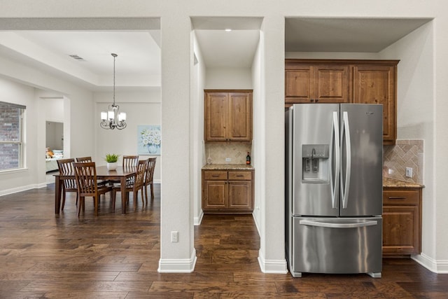 kitchen with dark wood-style flooring, visible vents, brown cabinetry, light stone countertops, and stainless steel fridge with ice dispenser