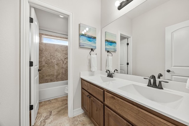 bathroom featuring double vanity, a sink, toilet, and baseboards