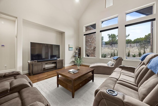 living area with light wood-style floors, baseboards, and high vaulted ceiling