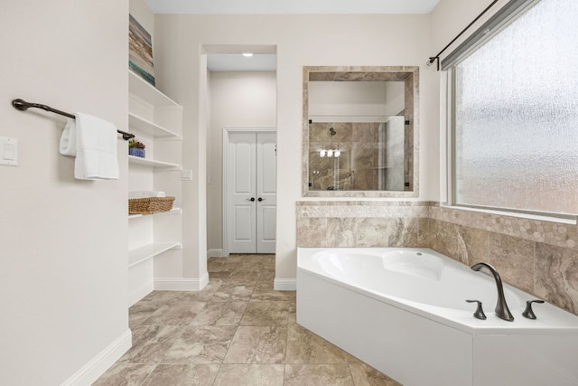 full bathroom with a stall shower, baseboards, and a bath