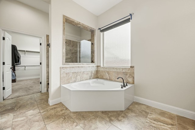 bathroom featuring a garden tub, baseboards, a walk in closet, and a shower stall