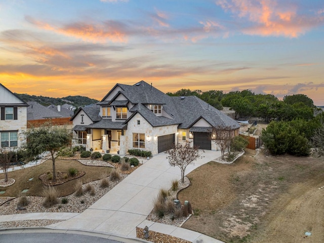 view of front of property with driveway, stone siding, a garage, and covered porch