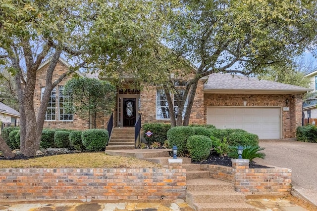 view of front facade with an attached garage, driveway, roof with shingles, and brick siding