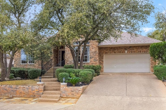 view of front of property with a garage, a shingled roof, concrete driveway, and brick siding