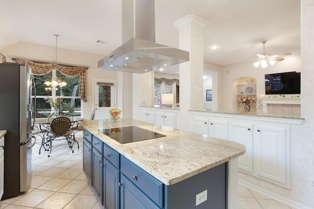 kitchen featuring black electric stovetop, freestanding refrigerator, island range hood, blue cabinets, and ceiling fan with notable chandelier