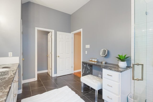 bathroom with a stall shower, vanity, baseboards, and tile patterned floors