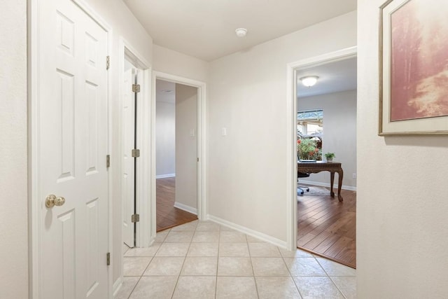 hallway featuring light tile patterned floors and baseboards