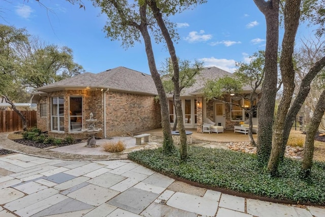 rear view of house with brick siding, fence, a sunroom, roof with shingles, and a patio area