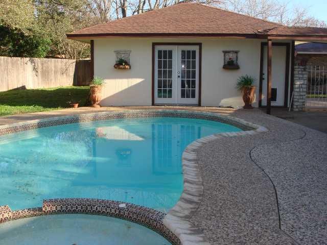 view of swimming pool featuring a pool with connected hot tub, fence, and french doors