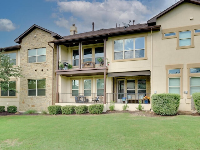 rear view of property with stone siding, a lawn, and stucco siding