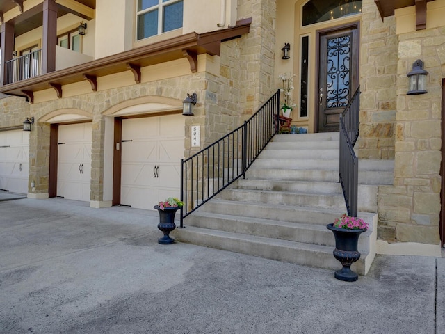 doorway to property with a garage, stone siding, and driveway