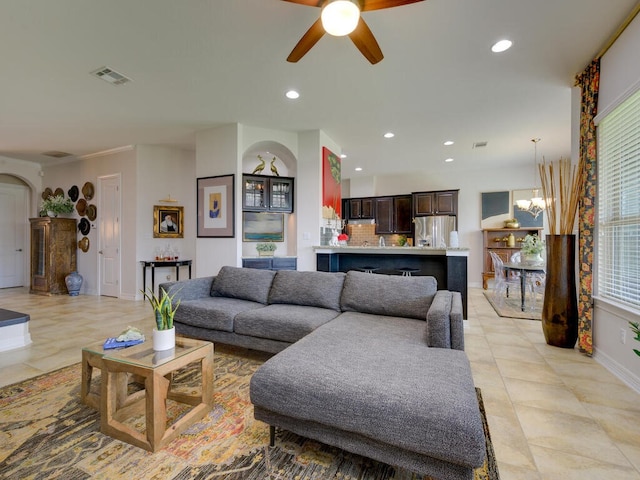 living area featuring arched walkways, ceiling fan with notable chandelier, visible vents, and recessed lighting