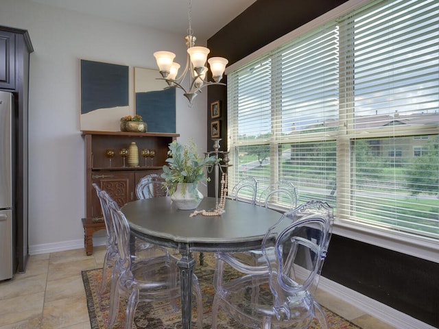 dining area featuring an inviting chandelier, light tile patterned floors, and baseboards