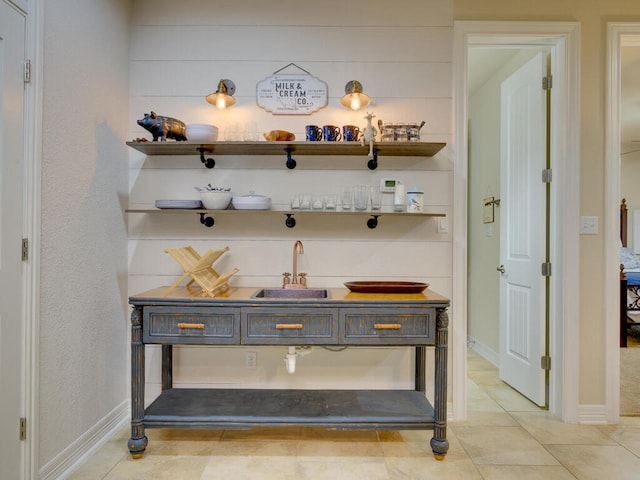 bar featuring wet bar, a sink, baseboards, and light tile patterned floors