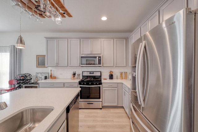 kitchen featuring pendant lighting, light wood-type flooring, backsplash, appliances with stainless steel finishes, and recessed lighting